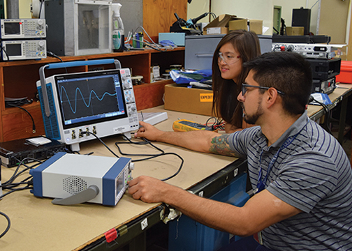 Engineers working at desk on electrical monitors 